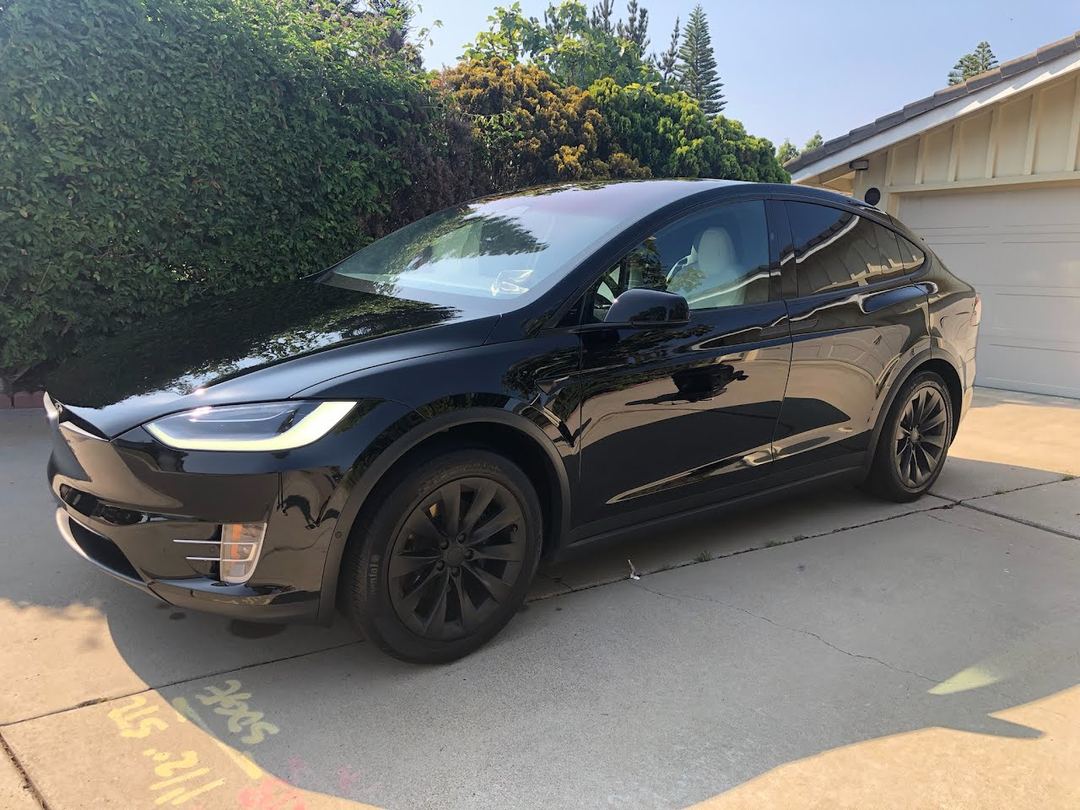 Black Tesla Model X after an exterior mobile detail in a home driveway